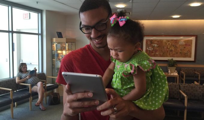 Father participates in TFP's father engagement survey at MGH Vincent Obstetrics while holding his baby daughter.