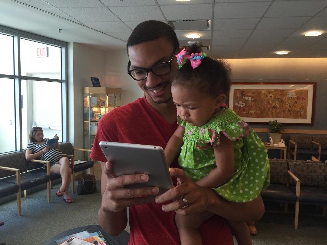 Father participates in TFP's father engagement survey at MGH Vincent Obstetrics while holding his baby daughter.